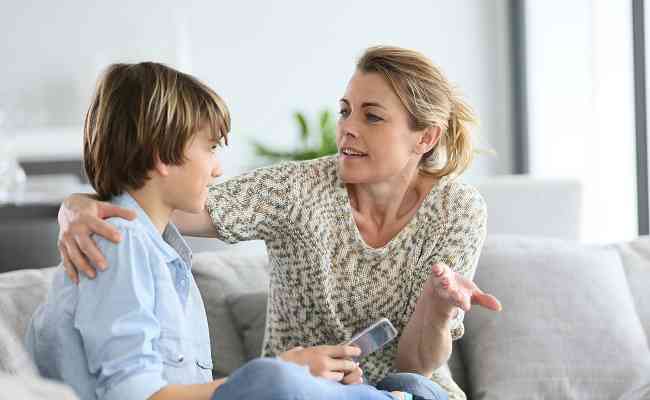 Mother giving warning to young boy using smartphone